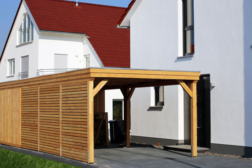 House exterior with flat roof carport made of wood, and driveway