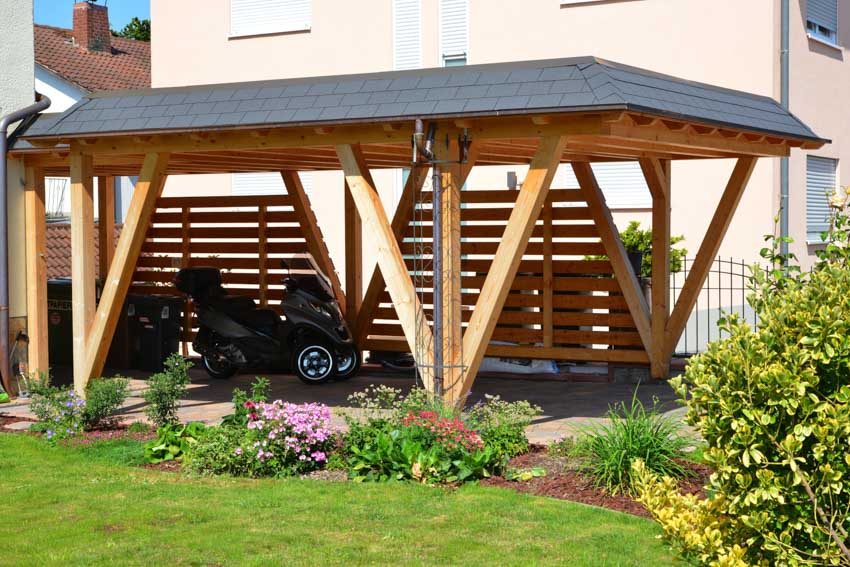 House exterior with tandem carport, shingle roof, lawn plants, and flowers