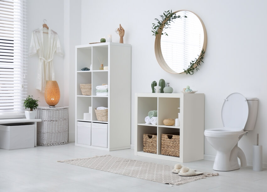 Beautiful interior of bathroom with round mirror, toilet, storage cabinet shelves and other bathroom accessories