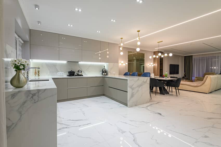 Kitchen dining area and living room combined with Statuario marble floor, countertops, white cabinets, backsplash, ceiling lights, table, chairs, and couch
