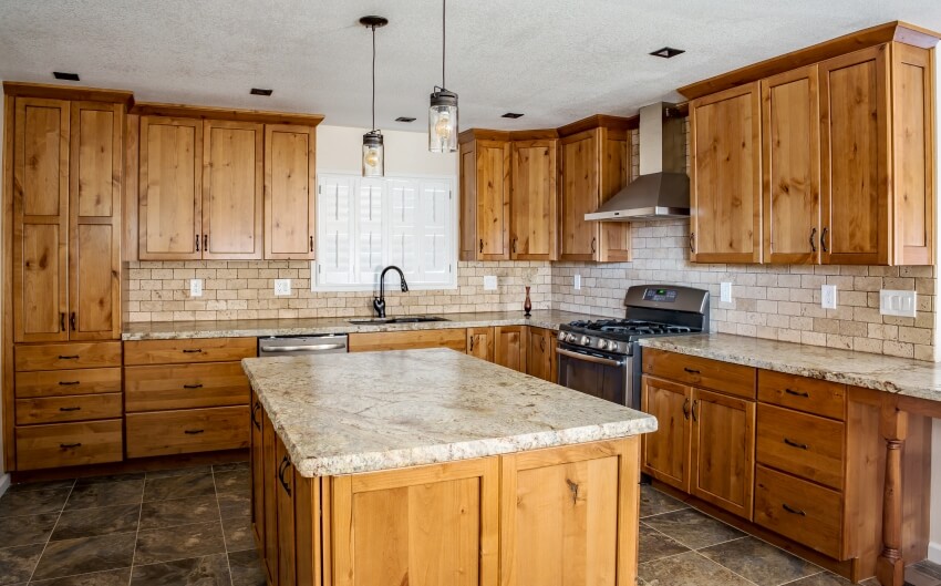 Kitchen with vertically oriented backsplash tiles and natural stone flooring