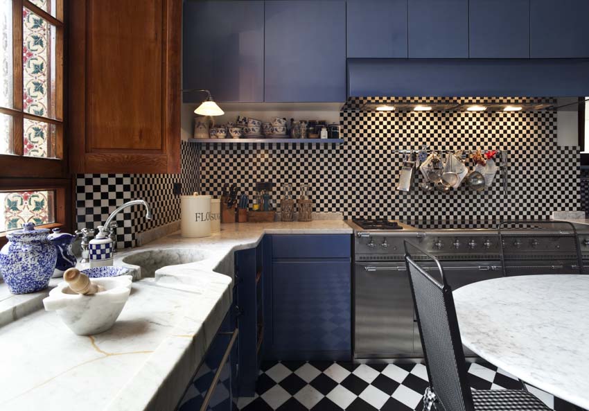 Kitchen with veined quartzite stone countertop, backsplash, blue cabinets, and patterned floor