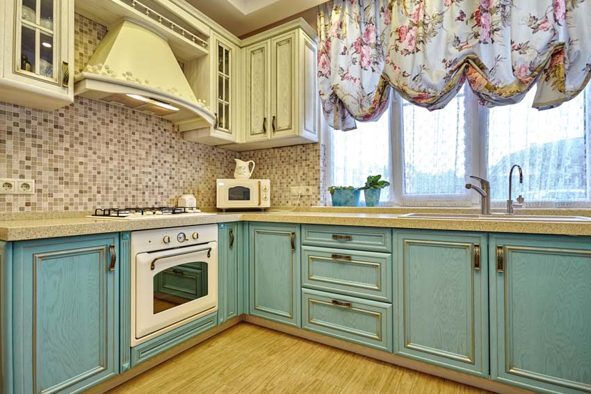 Kitchen with balloon shades, green cabinets, backsplash, windows, countertop, and range hood