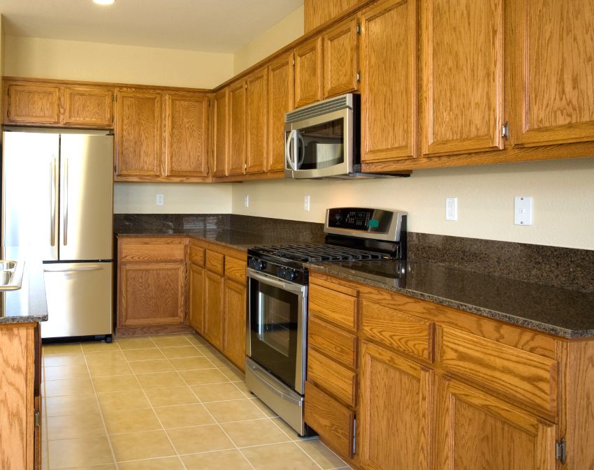 Kitchen with black granite counters, tile floor, stainless steel appliances and oak cabinets
