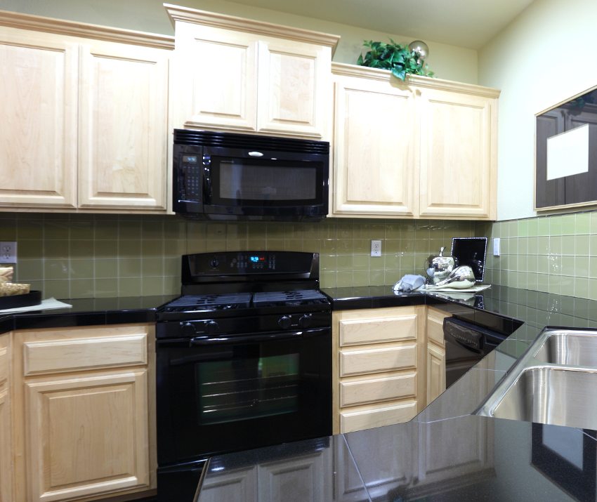 Kitchen with black granite countertop, white oak cabinets, and black appliances