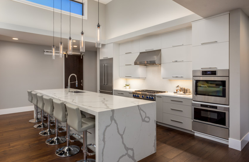Modern kitchen with quartz countertops, waterfall island and white flat panel cabinets