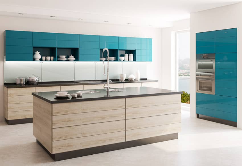 Kitchen with center island, black countertops, faucet, cabinets, and backsplash