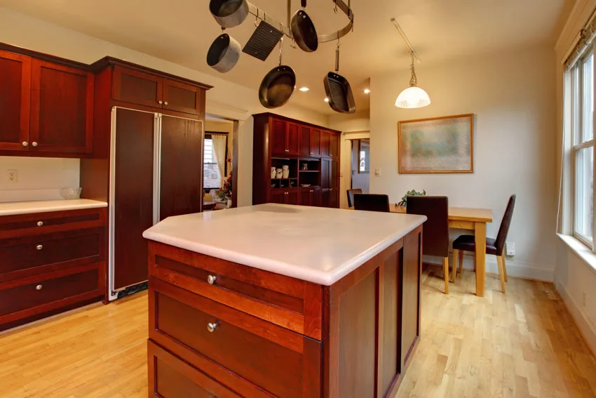 Kitchen with island, cherry mahogany cupboards, white countertop and overhead pots