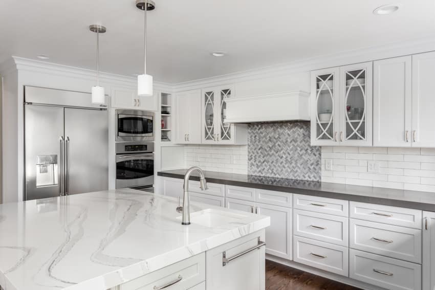 Kitchen with center island, Statuario marble countertop, cabinets, drawers, hanging lights, and backsplash