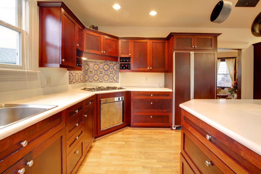 Kitchen with countertops, windows, backsplash, cherry cabinets, drawers, and ceiling lights