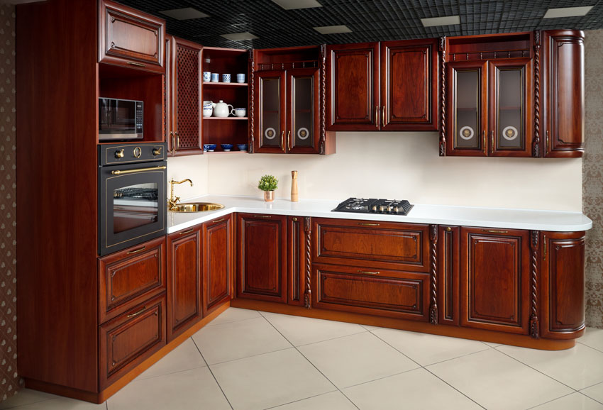 Kitchen with dark Bombay mahogany wood cabinets, tile floors, backsplash, stove, and oven