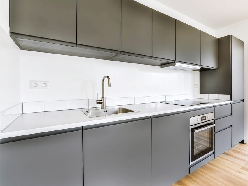 Kitchen with gray cabinets, under cabinet lights, sink and oven