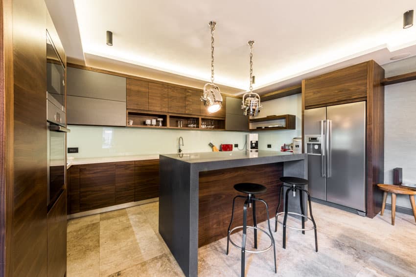 Kitchenw ith wood laminate cabinets, grey counter and black stools