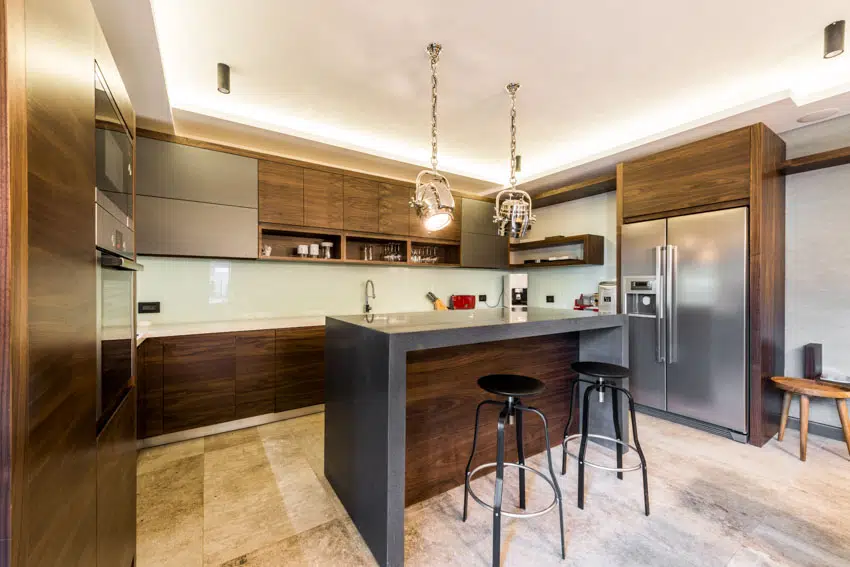Kitchen with limestone tile floors, walnut cabinets, bar area, stools, countertop, backsplash, and pendant lights