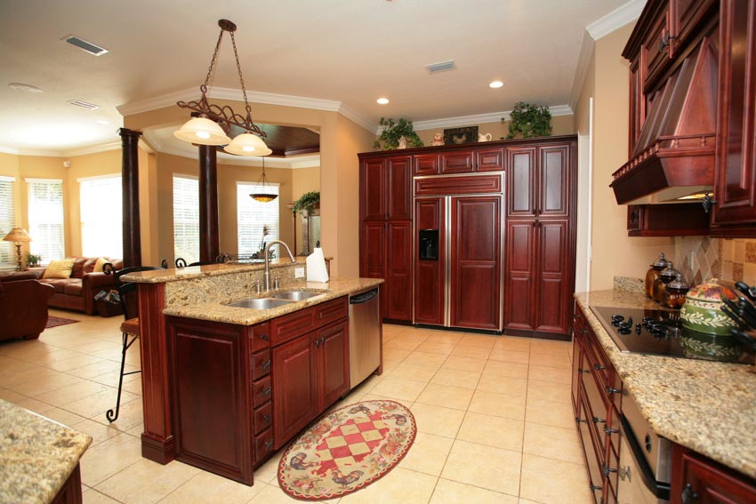 Kitchen with mahogany cabinets, center island, tile floors, hanging lights, countertops, and indoor plants