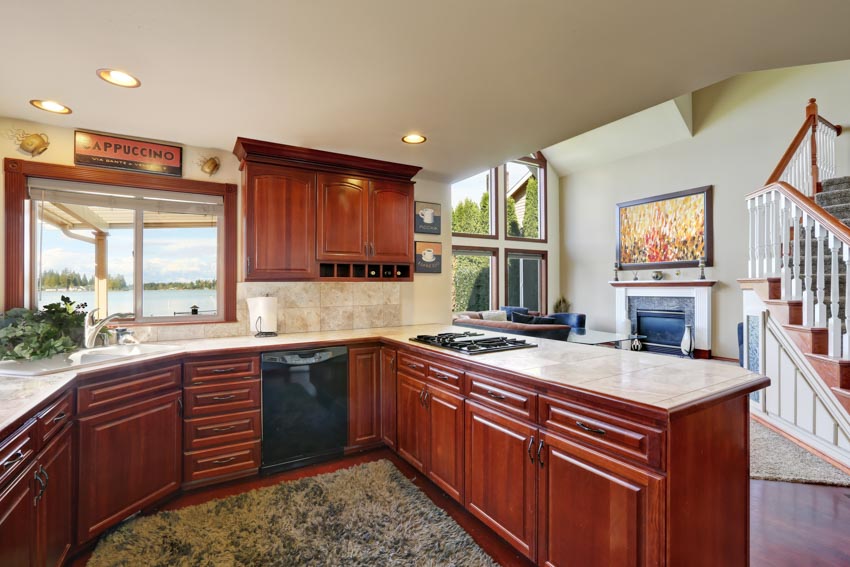 Kitchen with mahogany cabinets, countertops, induction stove, oven, ceiling lights, and windows