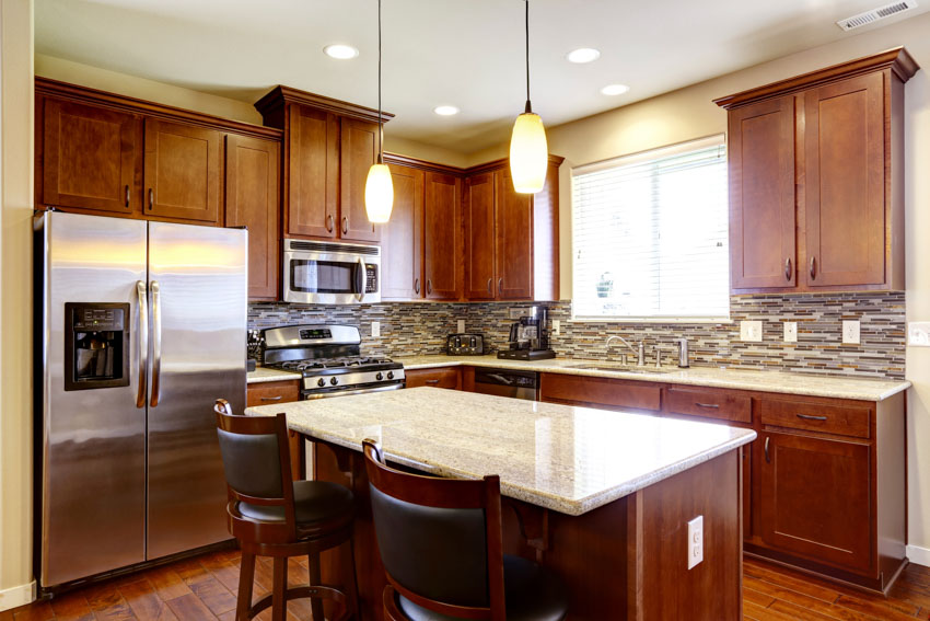 Kitchen with mahogany cabinets, island, countertop, backsplash, hanging lights, chairs, refrigerator, and window