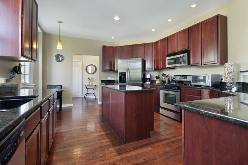 Kitchen with mahogany cabinets, wood floors, center island, drawers, oven, and stove