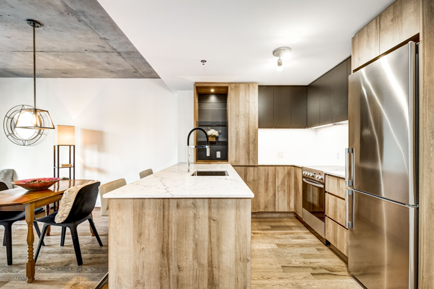 Kitchen with peninsula, wood floor, countertop, sink, faucet, backsplash, cabinets, oven, and refrigerator