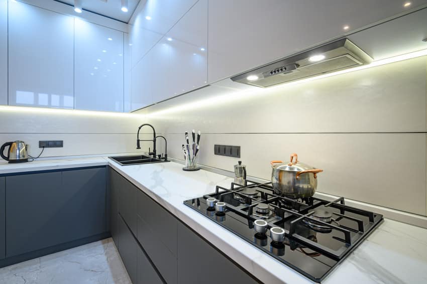 Kitchen with Statuario marble countertop, stove, range hood, backsplash, and white cabinets