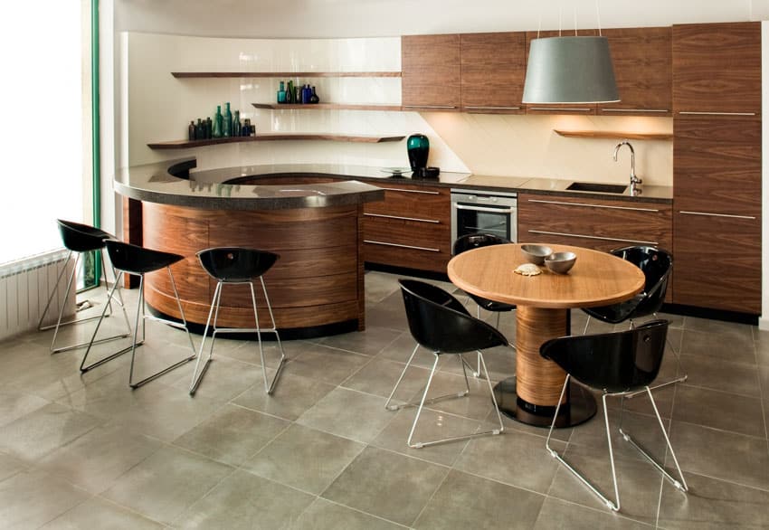Kitchen with Walnut cabinets, round table, chairs, stone tile floors, floating shelves, and pendant light