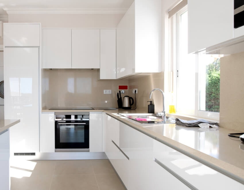 Kitchen with glossy cabinets, beige style backsplash and window