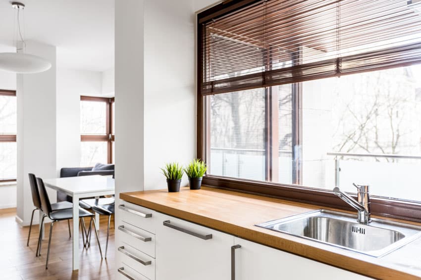 Kitchen with butcher block countertop, sink, window, and white drawers