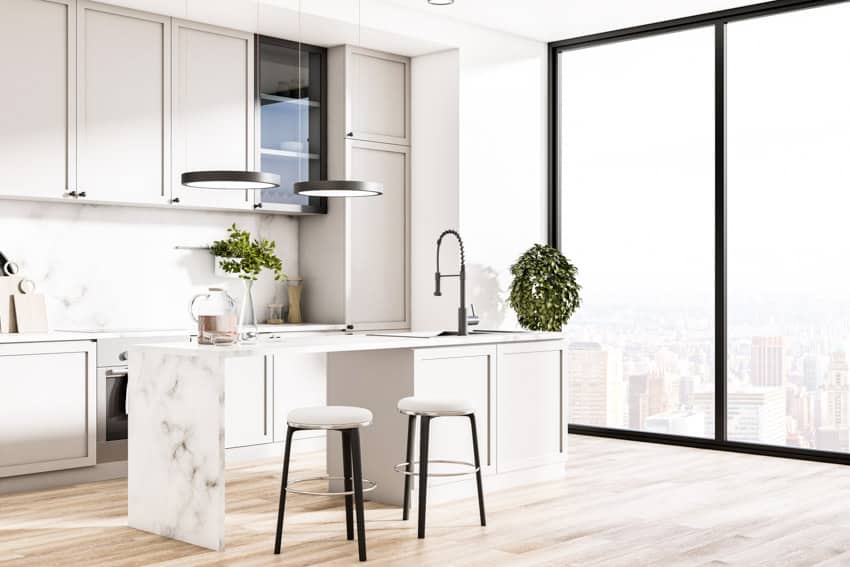 Kitchen with wood floors, window, stools, island, countertop, backsplash, cabinets, and faucet in island