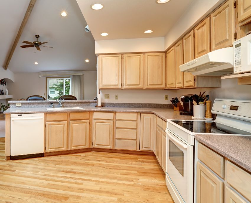 A large hardwood floor kitchen with white oak wood cabinets and white appliances