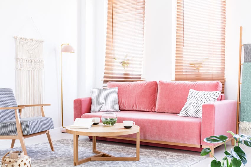 Room with pink couch, table, carpet floor, chair and lamp