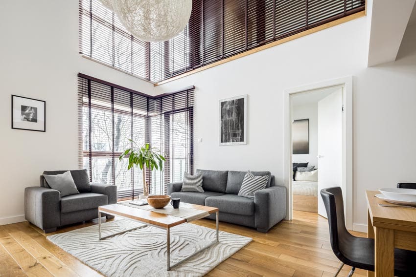 Room with blinds, grey sofa, glass topped center table and white walls