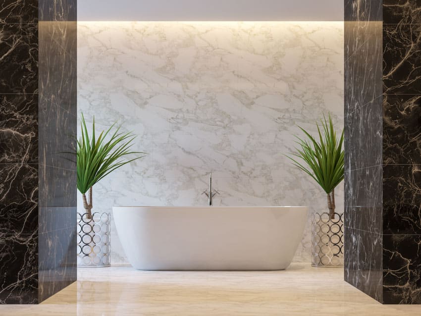 Minimalist bathroom with tub, bookmatched porcelain wall, and indoor plants