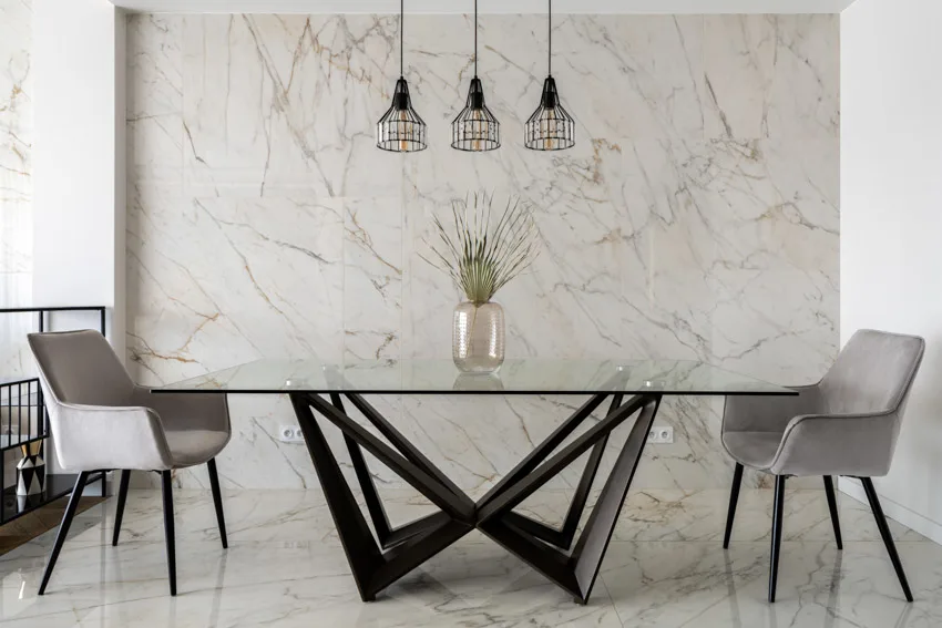 Modern dining room with bookmatched Statuario quartz wall, glass table, chairs, and pendant lights