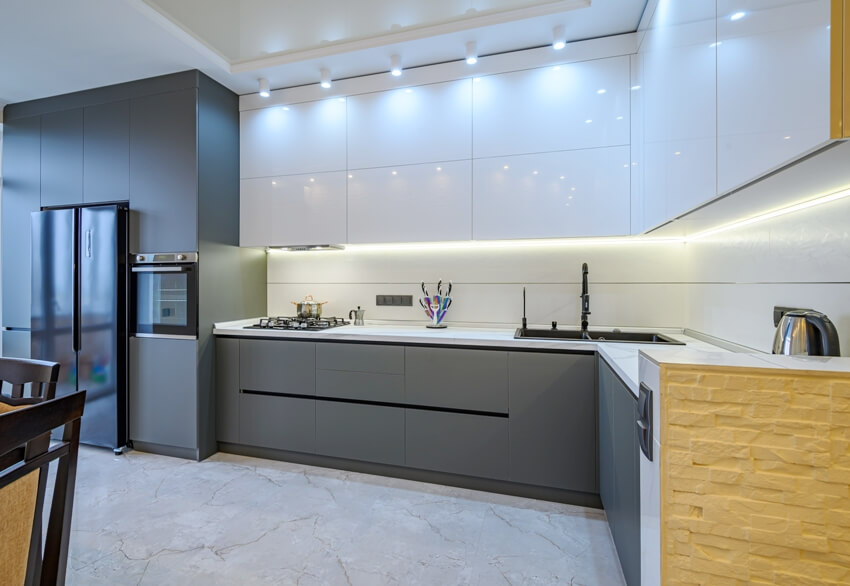 Kitchen with marble floors, black appliances, frameless cabinets and track lighting