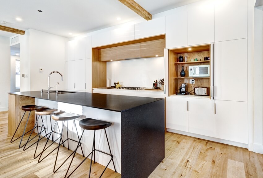 Kitchen with wood floors, waterfall style island and four stools