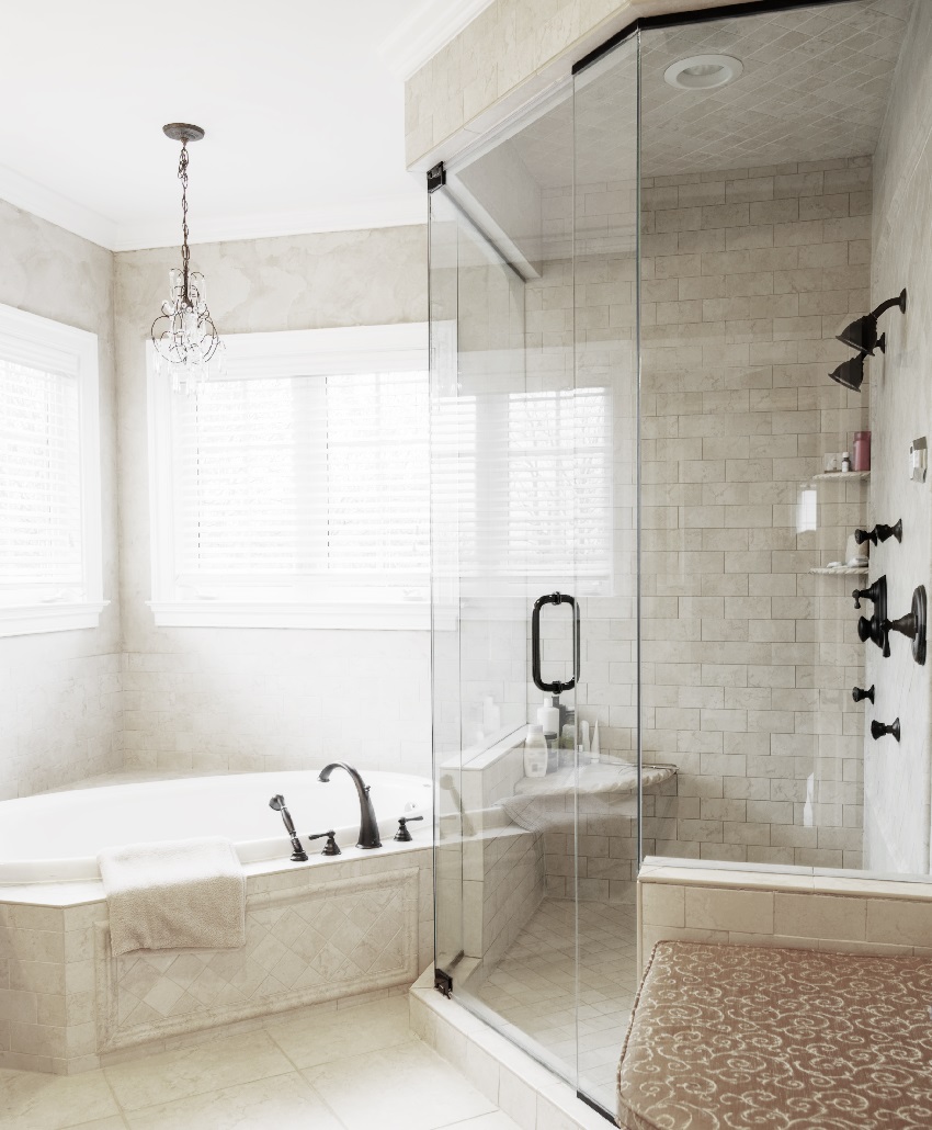 Neutral toned bathroom interior with hot tub tub and shower with glass doors and ceiling tiles