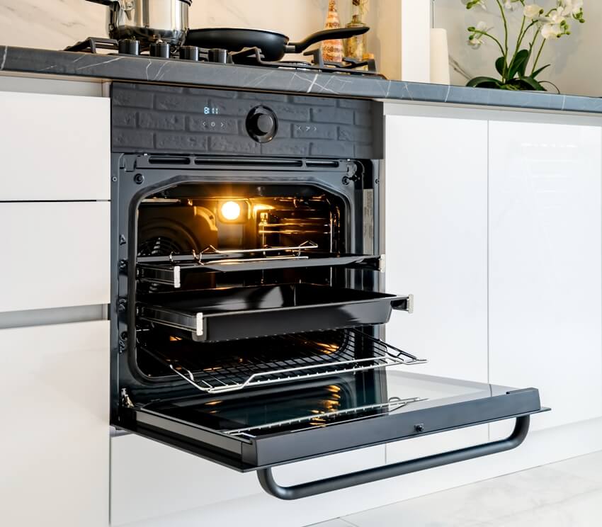 An open electric oven in a white kitchen interior 