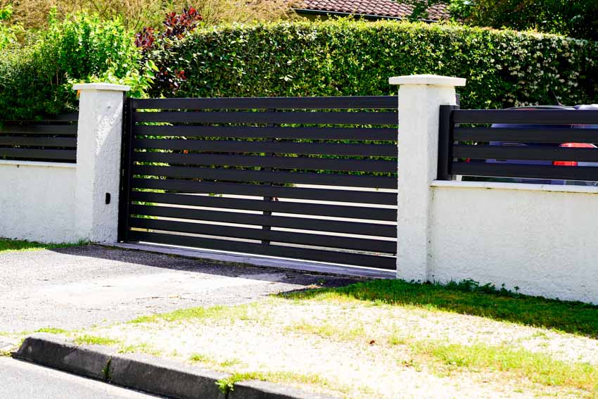 Black driveway fence and white wall