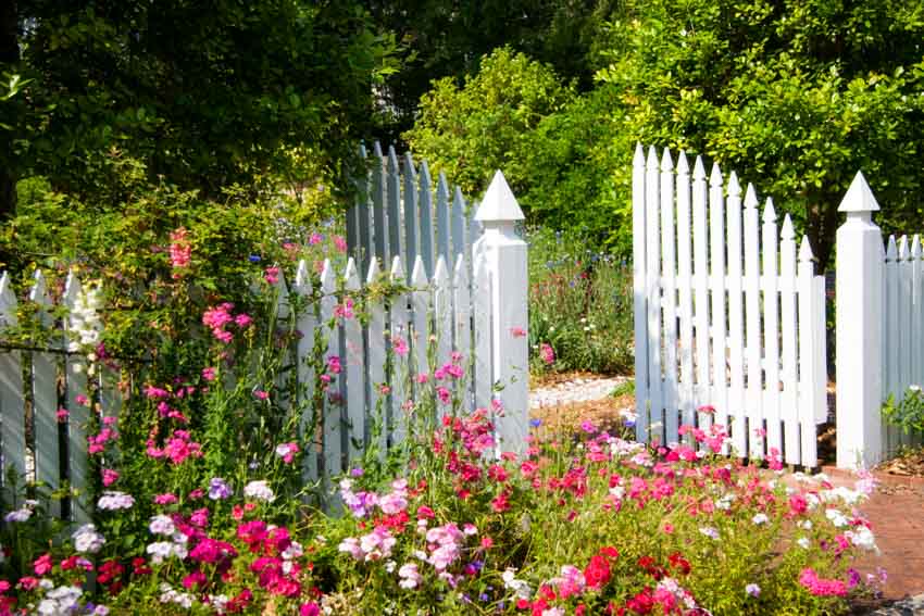 Open vinyl garden gate, flowers and plants