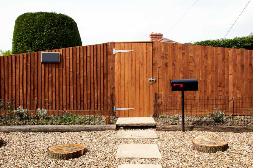 Outdoor area with tongue and groove overlapping fence, gate, mailbox, gravel, and walkway