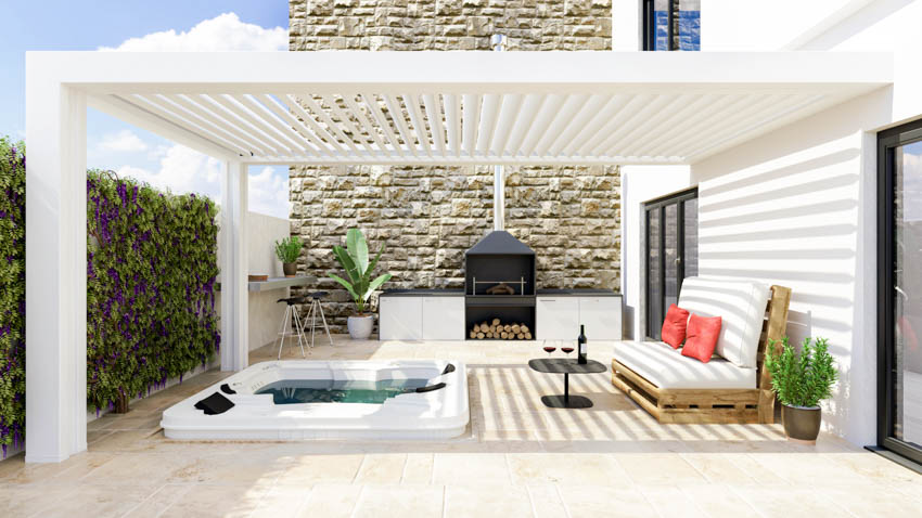 Outdoor area with privacy wall, white pergola, hot tub, couch, fireplace, and plants