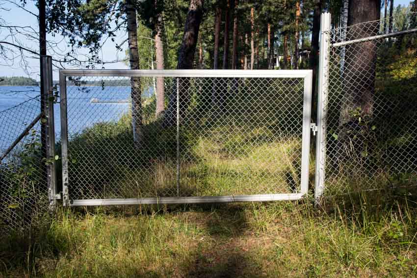 White chain link fence with grassy driveway