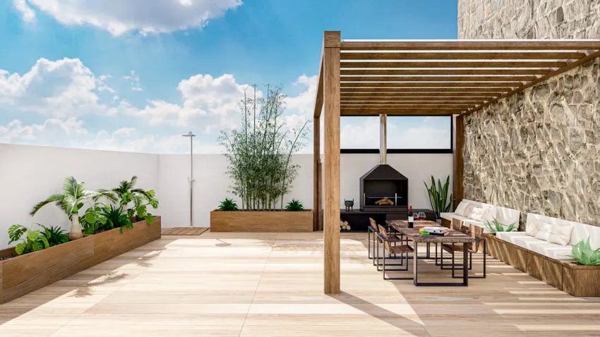 Outdoor deck with pergola privacy wall, wood flooring, cushioned couches, chairs, tables, and plant beds