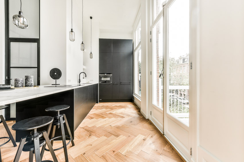 Peninsula seating for kitchens with wood herringbone floors, black door, and windows