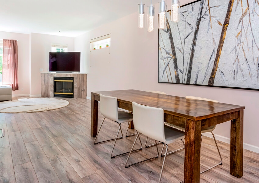 Rustic dining area with porcelain tiles, framed artwork hanging on wall, wooden table and leather chairs