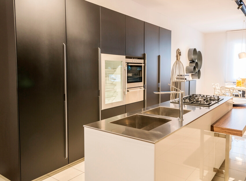 A simple minimalist kitchen interior with black euro style cabinets and island with stainless steel countertop and sink