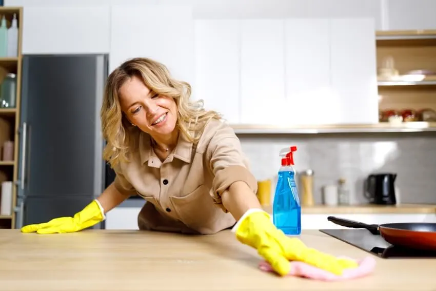 A smiling woman cleaning kitchen countertop