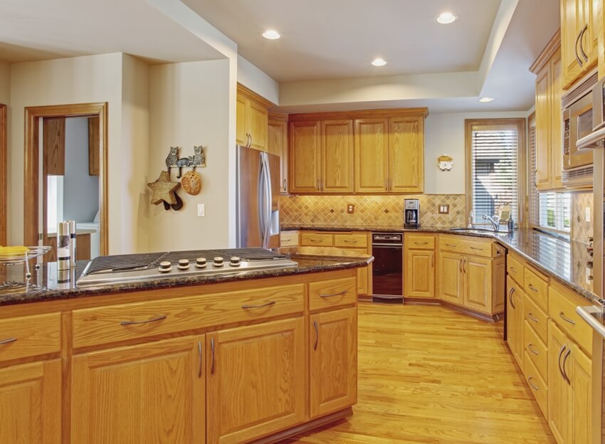 Kitchen with white ceiling, black countertops with wood base and windows