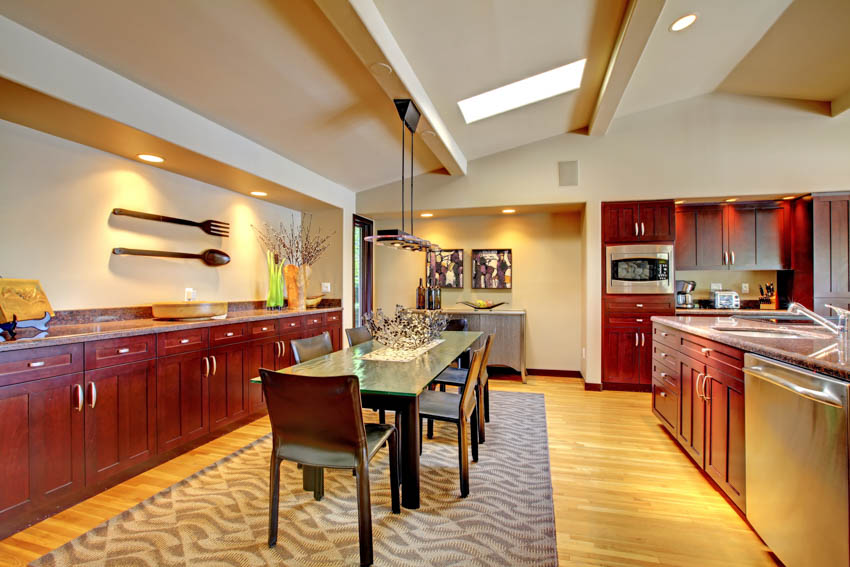 Spacious kitchen with dining table, chairs, mahogany cabinets, sloped ceiling, and wood flooring