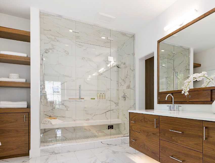 Stunning bathroom interior with big mirror above wooden cabinets, marble floors and shower ceiling tile